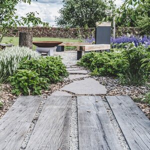 Detail chodníku ze zahradních pražců, v pozadí designové lavičky vyrobeny z pražců a kovových nohou. Zakázková výroba Impregnace Soběslav.