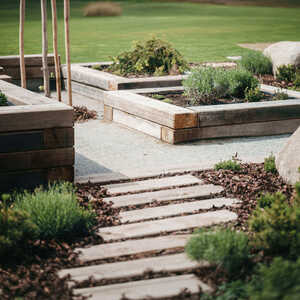 Elegantní chodník ze zahradních pražců, v pozadí praktické využití pražců k vymezení záhonů.