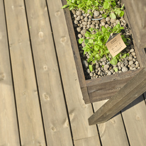 Ručně vyrobený květináč z impregnovaného dřeva umístěn na terase z KI prken. 