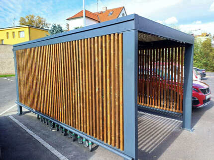 Obložení boční strany přístřešku pro nákupní vozíky fasádními hranoly KI (formát 45x45 mm) v hnědém odstínu - nová prodejna Billa v Žatci.  