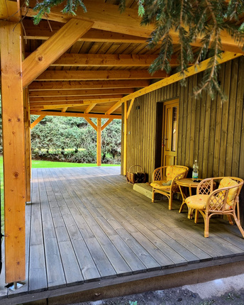 Detail terasy rekreačního domu, která je obložena terasovými prkny KI Duo, v pozadí obložení fasády fasádním obkladem KI Trend v šedé barvě.   