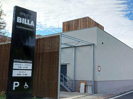 Detail opláštění části fasády obkladovými hranoly KI (formát 45x45 mm) v hnědém odstínu, v pozadí opláštění střešních vývodů vzduchotechniky obkladovými prkny KI UNI (formát 19x148 mm) v hnědém odstínu - nová prodejna Billa v Žatci. Detail opláštění části fasády obkladovými hranoly KI (formát 45x45 mm) v hnědém odstínu, v pozadí opláštění střešních vývodů vzduchotechniky obkladovými prkny KI UNI (formát 19x148 mm) v hnědém odstínu - nová prodejna Billa v Žatci.