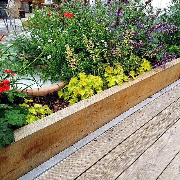 Detail nadzemního záhonu z impregnovaných zahradních pražců a terasy z impregnovaných prken z borovice, oboje Profi impregnace.