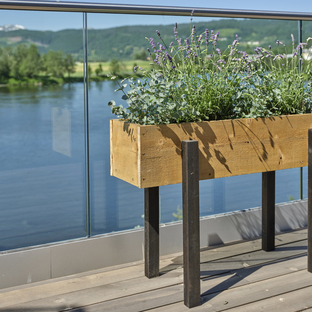 Ručně vyrobený květináč na dřevěných nohou na terase z prken KI.